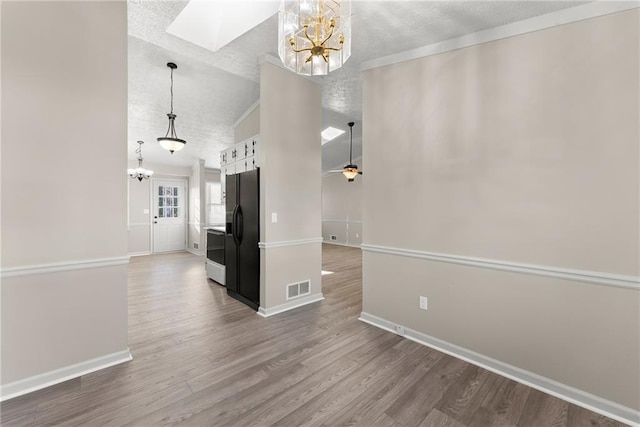 interior space featuring hardwood / wood-style floors, a textured ceiling, a skylight, and a chandelier