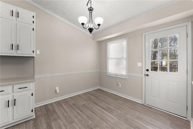 unfurnished dining area with a notable chandelier, plenty of natural light, and light wood-type flooring