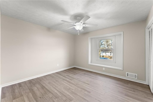 spare room featuring a textured ceiling, ceiling fan, and light wood-type flooring