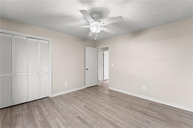 unfurnished bedroom featuring ceiling fan, a textured ceiling, a closet, and light wood-type flooring