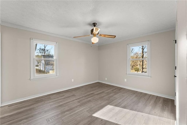 empty room with ceiling fan, a healthy amount of sunlight, light hardwood / wood-style flooring, and a textured ceiling