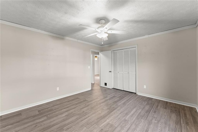 unfurnished bedroom featuring crown molding, wood-type flooring, a closet, and a textured ceiling