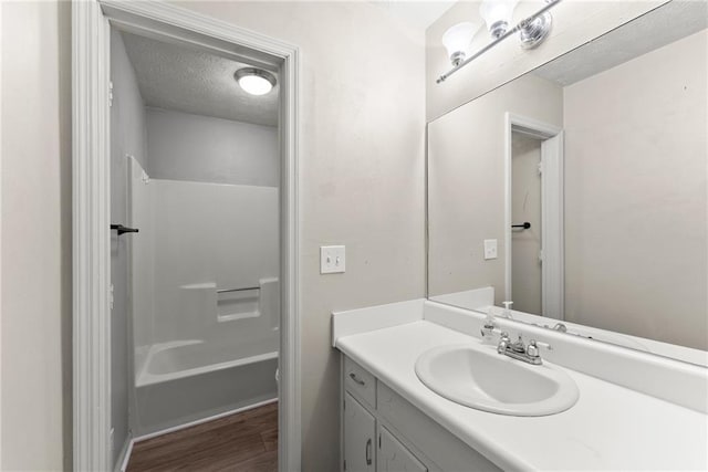 bathroom featuring vanity, hardwood / wood-style flooring, bathtub / shower combination, and a textured ceiling