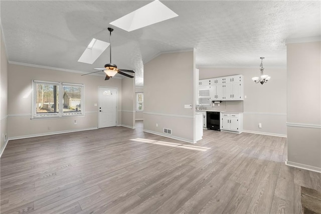 unfurnished living room with crown molding, ceiling fan with notable chandelier, light hardwood / wood-style flooring, and lofted ceiling with skylight