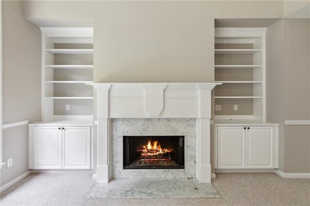 details featuring carpet flooring, a premium fireplace, baseboards, and built in shelves