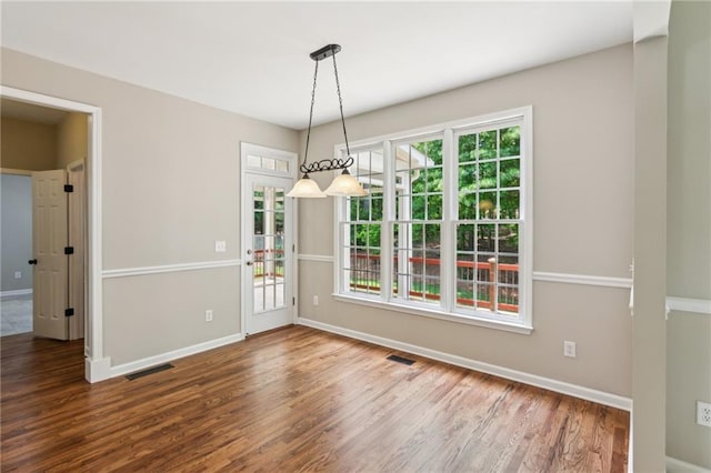 unfurnished dining area featuring visible vents, baseboards, and wood finished floors