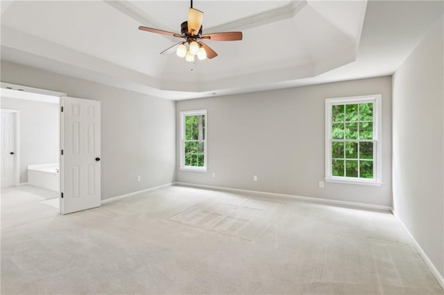 carpeted spare room with baseboards, ceiling fan, and a tray ceiling