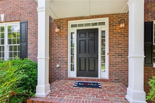 view of exterior entry with covered porch and brick siding