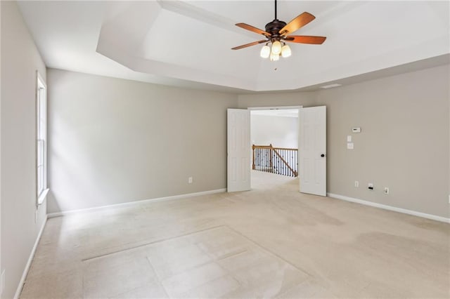 unfurnished room with baseboards, a ceiling fan, and a raised ceiling