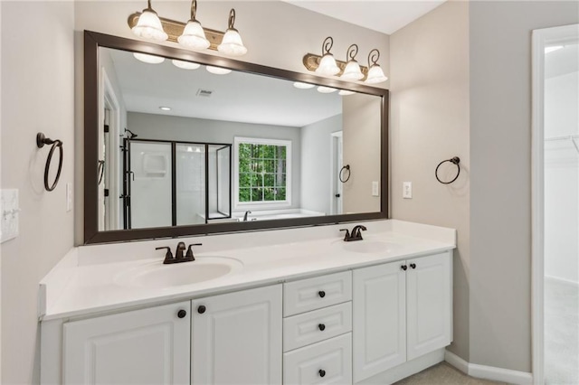 bathroom featuring a sink, a shower stall, double vanity, and visible vents