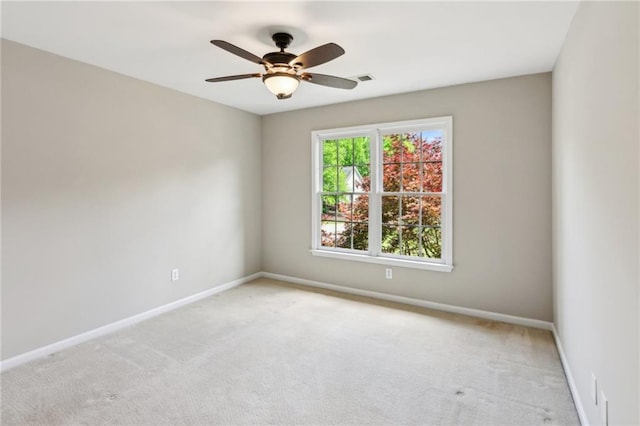 carpeted spare room with baseboards, ceiling fan, and visible vents