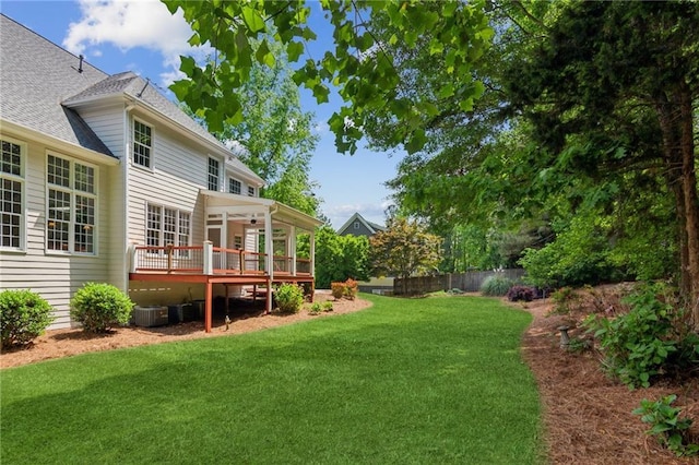 view of yard with fence, central AC unit, and a deck