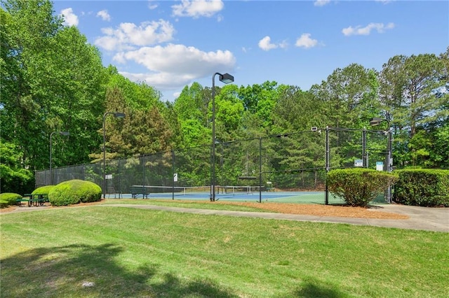view of property's community with a lawn, fence, and a tennis court