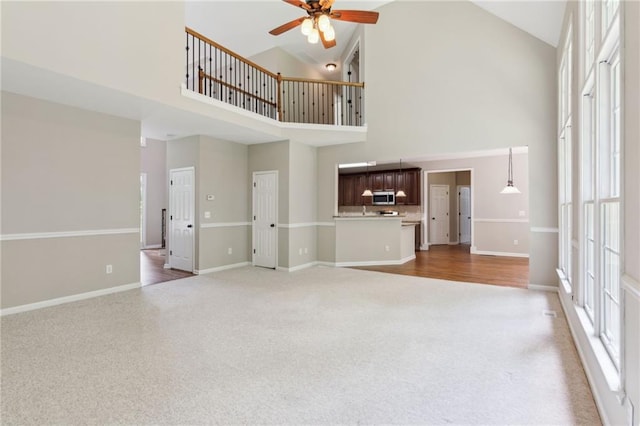 unfurnished living room featuring high vaulted ceiling, light colored carpet, a wealth of natural light, and ceiling fan