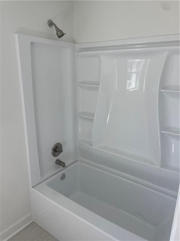 full bath featuring washtub / shower combination and baseboards