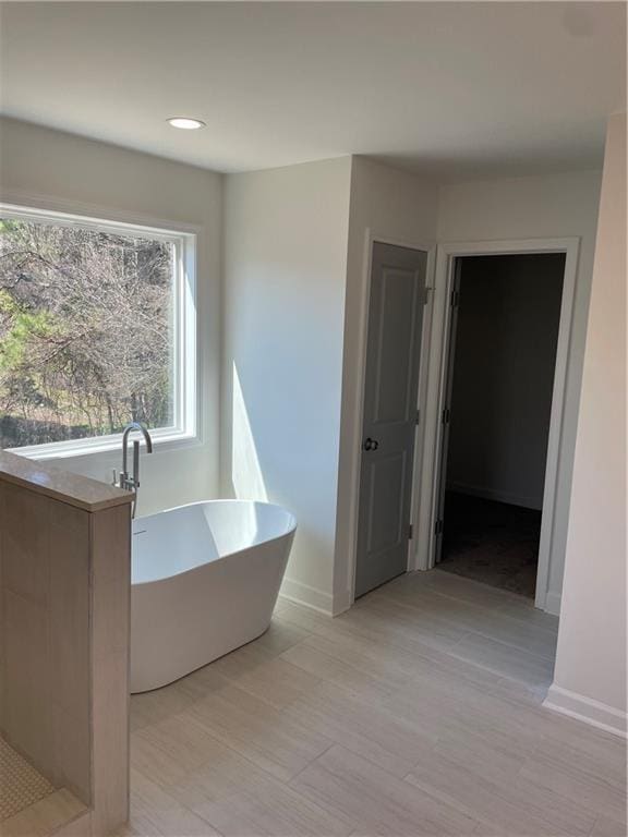 full bath featuring a freestanding bath and baseboards