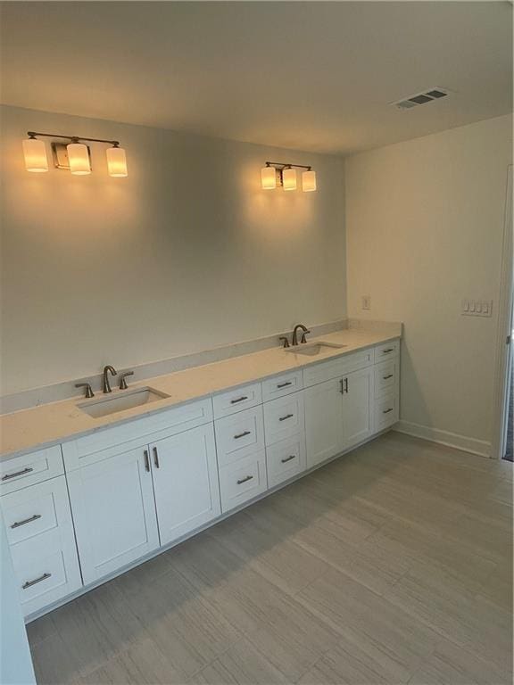 bathroom featuring double vanity, visible vents, baseboards, and a sink