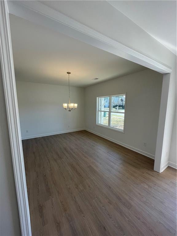 empty room featuring dark wood finished floors, baseboards, and a chandelier