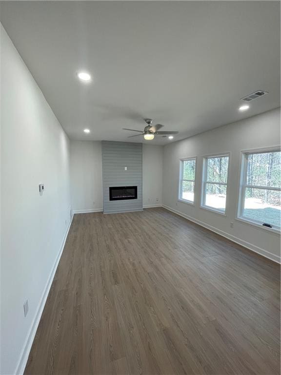 unfurnished living room featuring visible vents, a ceiling fan, a fireplace, baseboards, and dark wood-style flooring