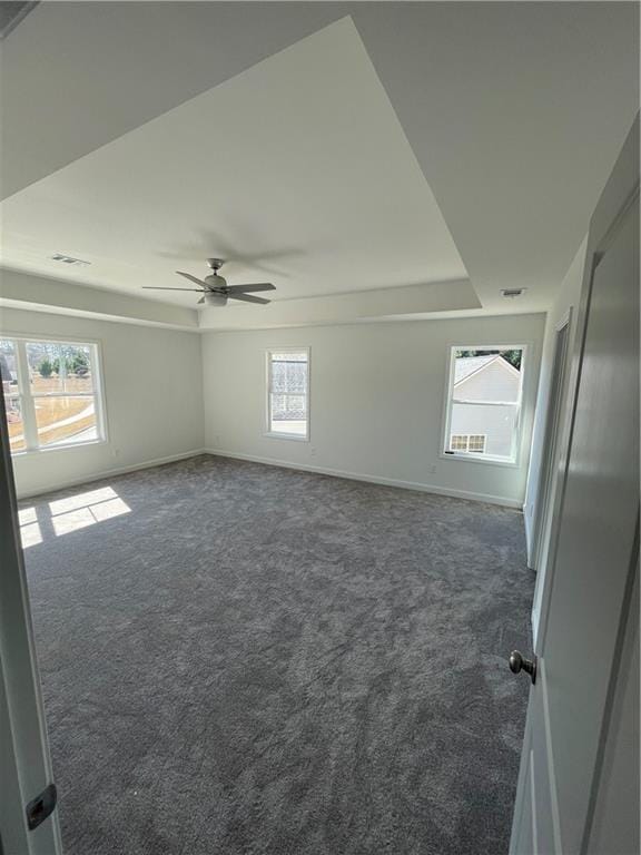 carpeted spare room with visible vents, baseboards, a wealth of natural light, and ceiling fan