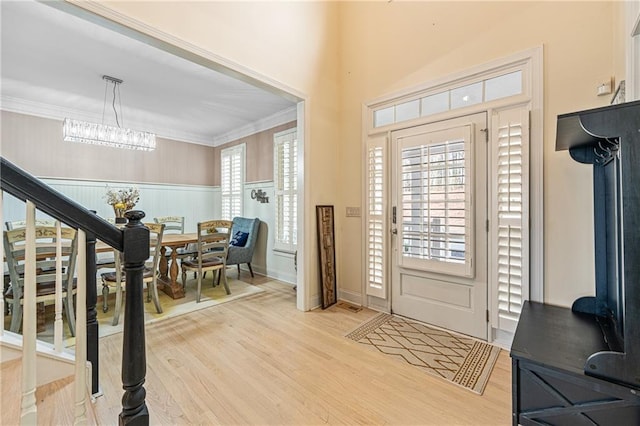 entrance foyer featuring light wood finished floors, plenty of natural light, stairway, and ornamental molding