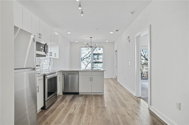 kitchen with a notable chandelier, white cabinets, decorative light fixtures, kitchen peninsula, and stainless steel appliances