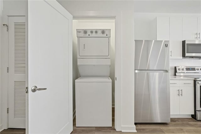 laundry room featuring light wood-type flooring and stacked washing maching and dryer