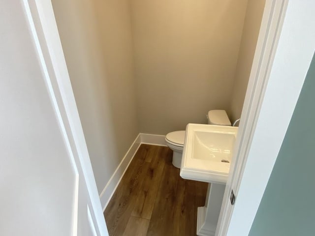 bathroom with toilet, baseboards, and wood finished floors