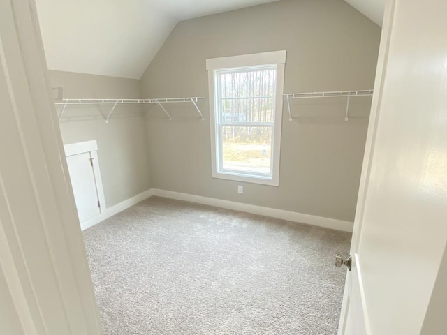 spacious closet featuring vaulted ceiling and light colored carpet