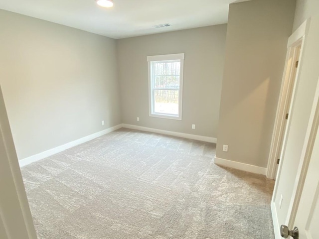 empty room featuring visible vents, light carpet, and baseboards