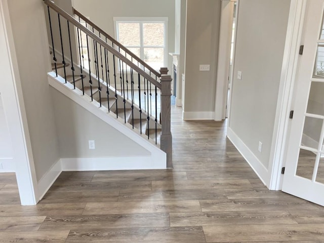 entryway with stairs, baseboards, and wood finished floors