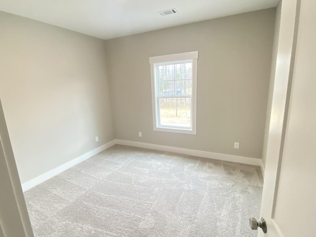 empty room with visible vents, light colored carpet, and baseboards