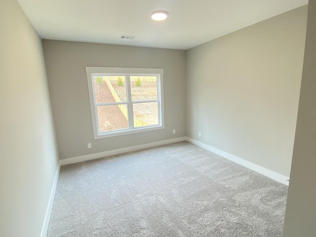 spare room with carpet flooring, visible vents, and baseboards