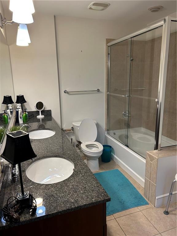 bathroom featuring vanity, tile patterned flooring, and combined bath / shower with glass door