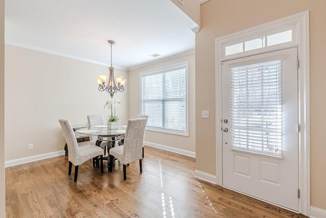 dining room featuring a chandelier, a healthy amount of sunlight, light wood-type flooring, and ornamental molding