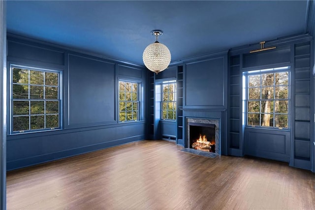 3051 Habersham Rd NW, Atlanta, GA 30305 - unfurnished living room with a decorative wall, a high end fireplace, a chandelier, crown molding, and wood finished floors