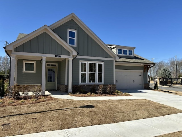 craftsman inspired home featuring concrete driveway, brick siding, board and batten siding, and a shingled roof