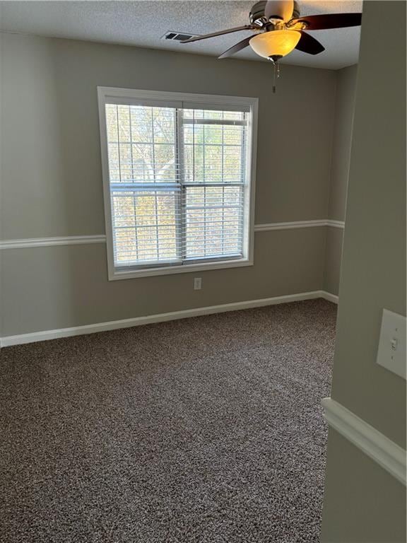 carpeted spare room featuring ceiling fan and a textured ceiling