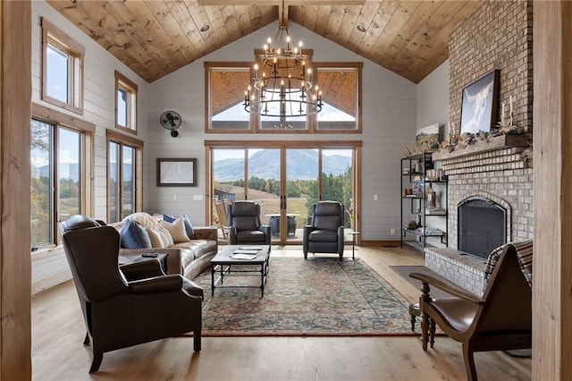 living room with wood ceiling, light hardwood / wood-style floors, a fireplace, high vaulted ceiling, and an inviting chandelier