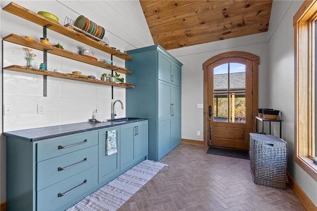 interior space featuring blue cabinets, sink, wood ceiling, backsplash, and lofted ceiling