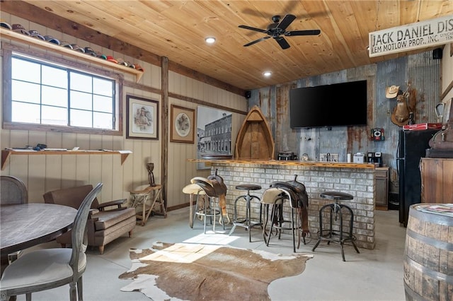 bar featuring wood ceiling, ceiling fan, and black fridge