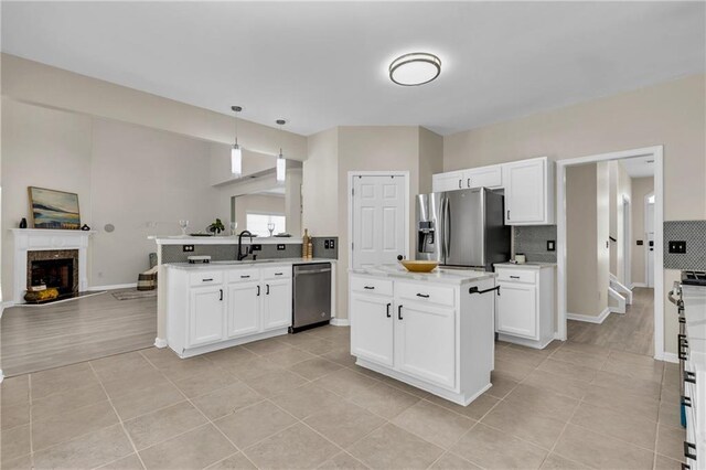 kitchen with stainless steel appliances, open floor plan, a peninsula, and light tile patterned floors
