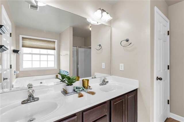 bathroom with a stall shower, a bath, and double vanity