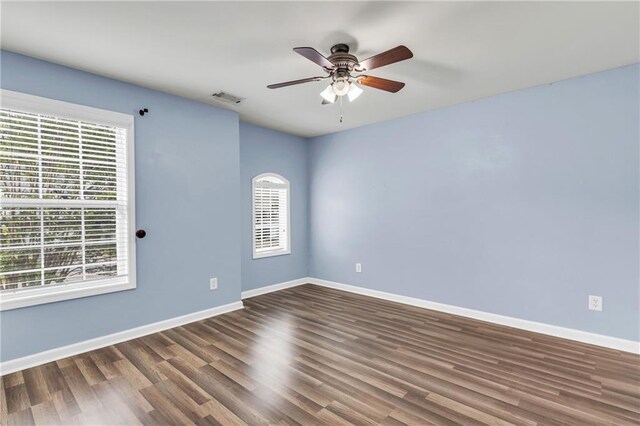 spare room with healthy amount of natural light, wood finished floors, and a ceiling fan