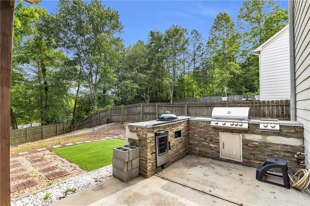view of patio / terrace featuring a grill, area for grilling, a fenced backyard, and view of scattered trees