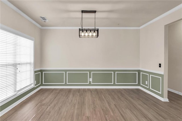unfurnished room featuring wood finished floors, ornamental molding, and wainscoting