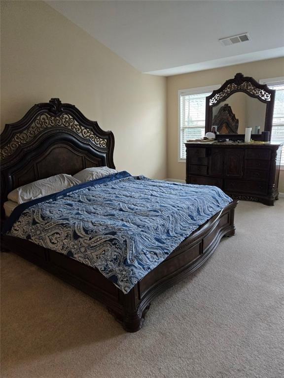 carpeted bedroom featuring visible vents