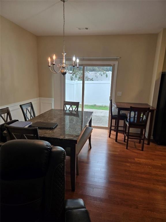 dining space with visible vents, an inviting chandelier, and wood finished floors