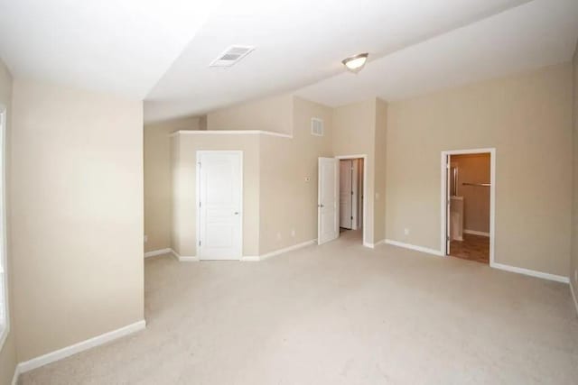 unfurnished bedroom with lofted ceiling, visible vents, light carpet, and baseboards