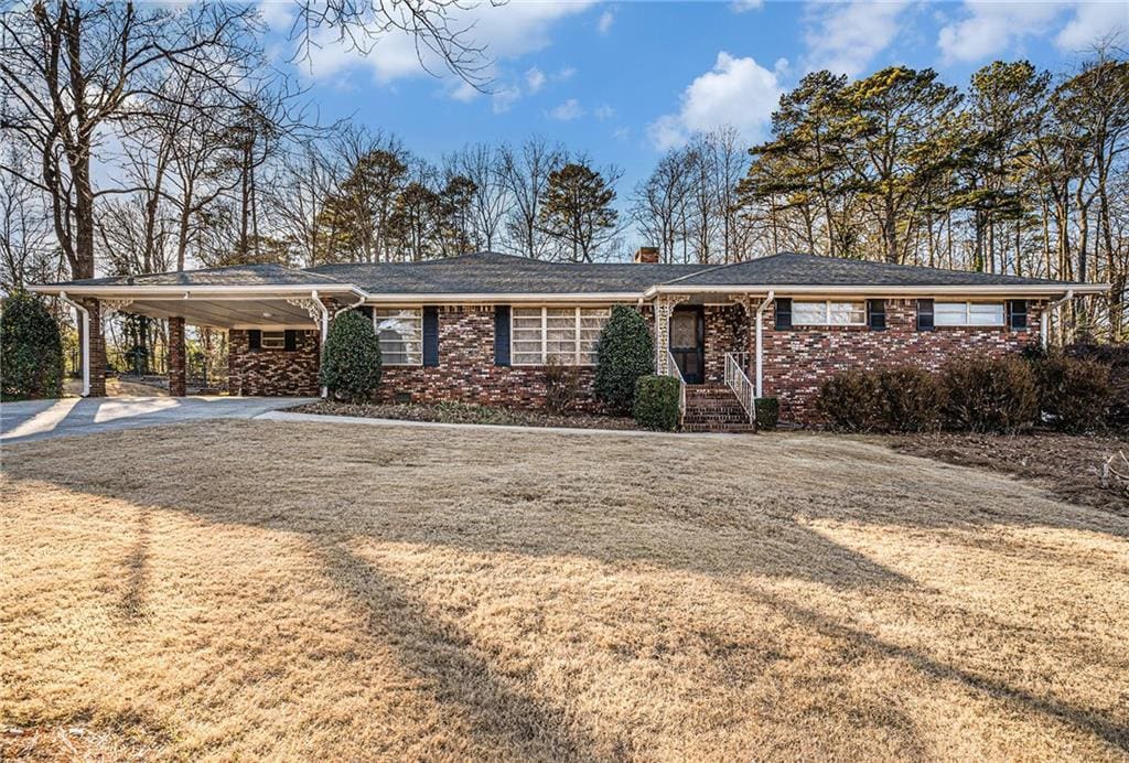 ranch-style home featuring a carport and a front lawn